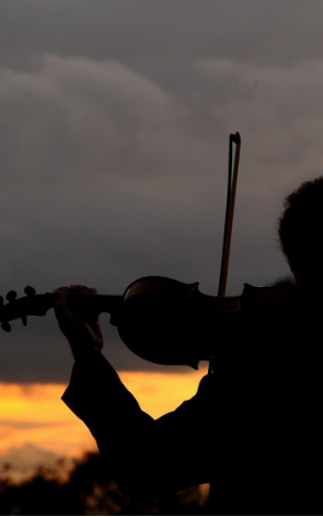 Carlos Zinanni tocando violino ao entardecer